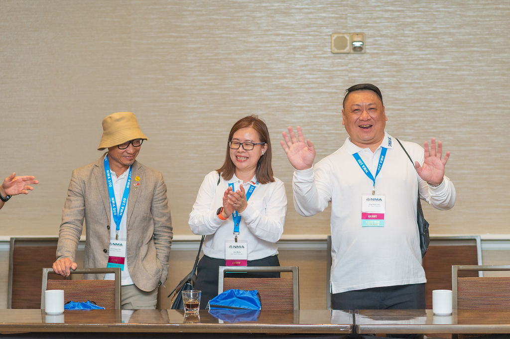 Conference attendees clapping and waving around a meeting table