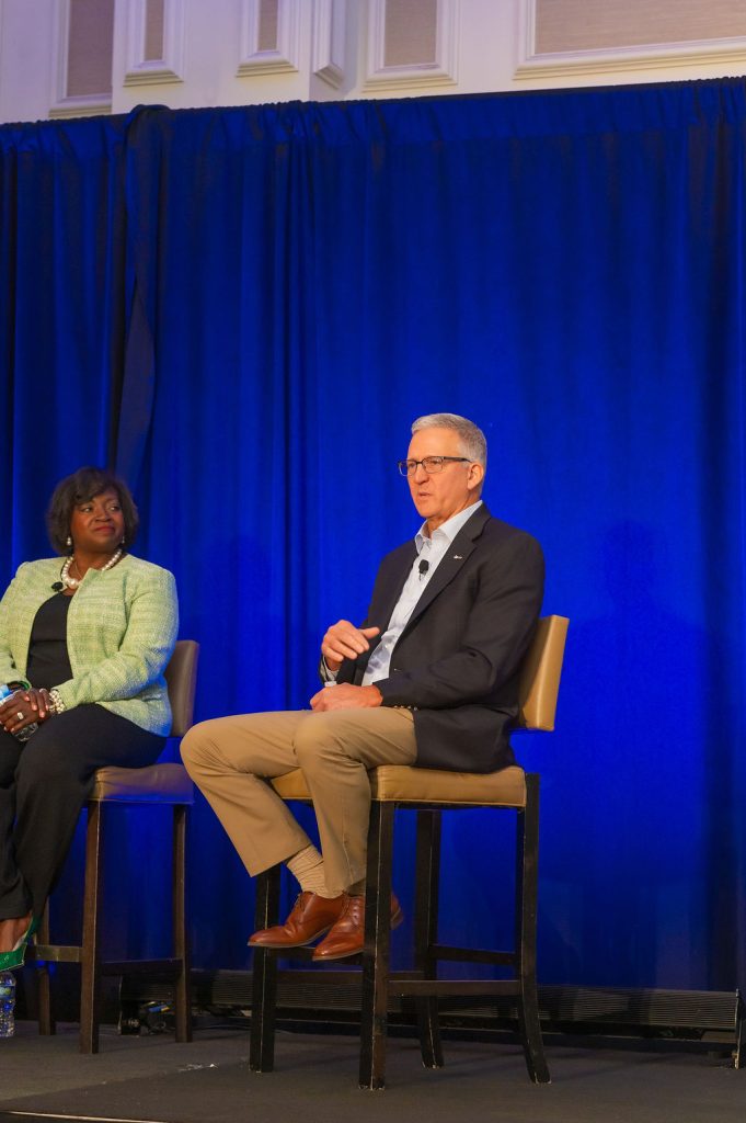 Two panelists in conversation on stage at an NMA conference
