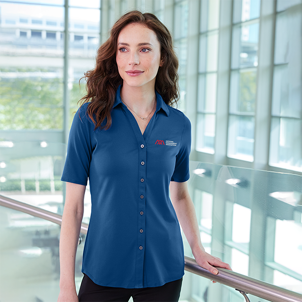 Woman In office in a blue NMA-branded polo shirt